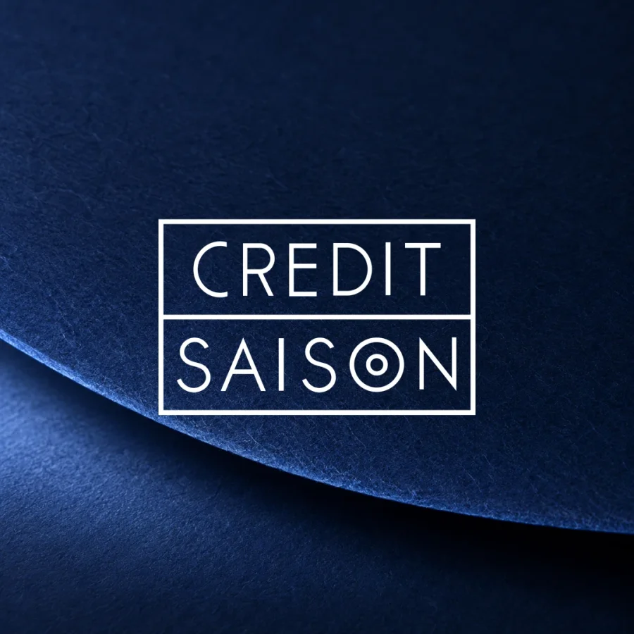 Credit Saison wordmark in white over a curved layer of textured navy paper.